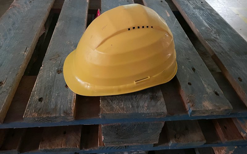 Un casque de chantier jaune posé sur du bois
